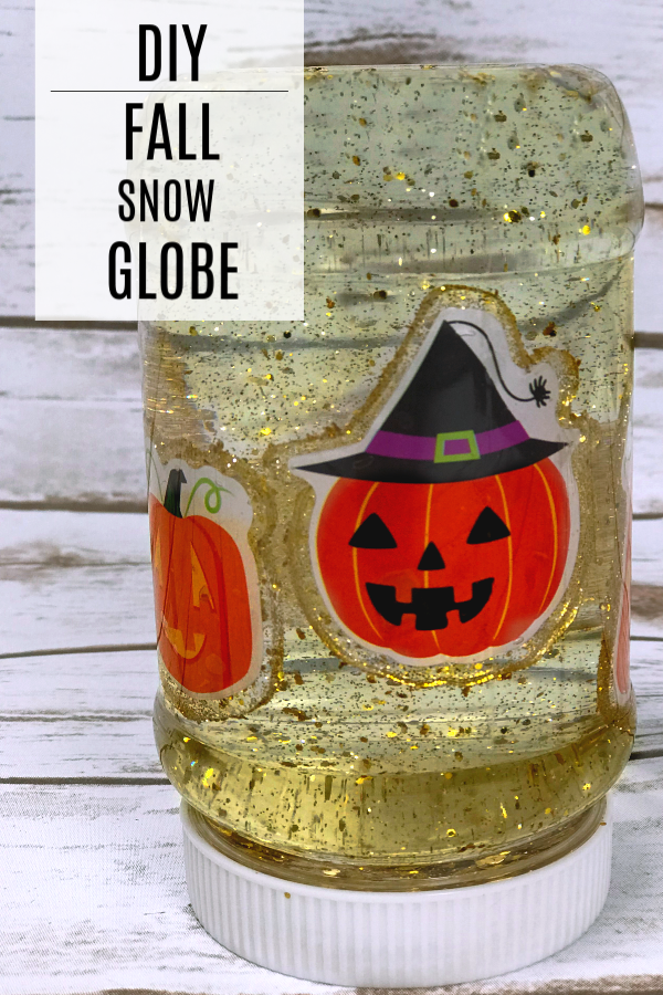 DIY snow globe in a plastic jar with gold glitter and pumpkin faces inside the jar. A fall activity for kids