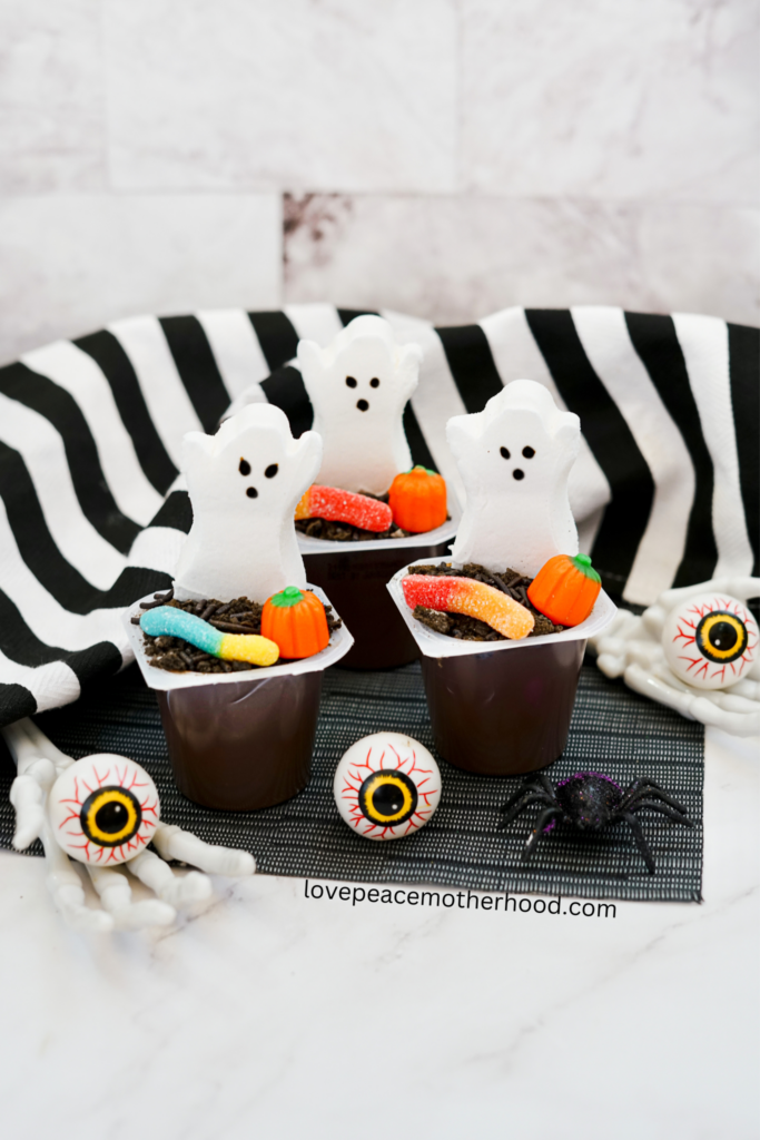 The Halloween Pudding Cups with the candy toppings. These individual pudding cups are filled with cookie-crumb dirt on top of the pudding. Each of them is topped with a marshmallow ghost and candy pumpkin. 