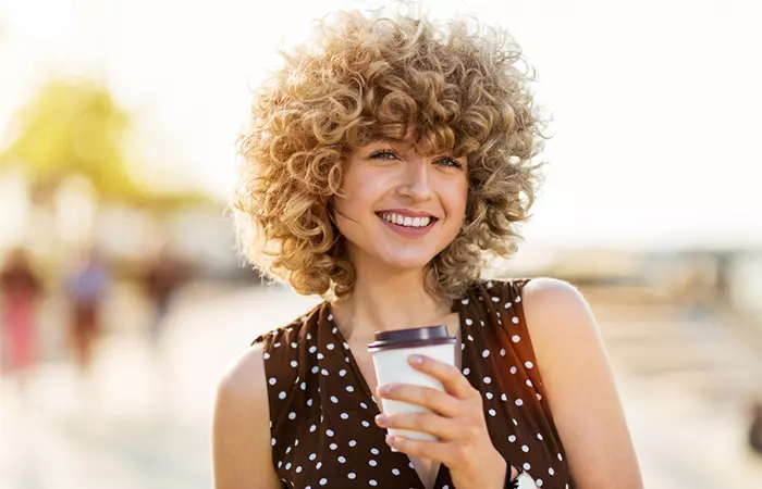 A happy woman with curly bangs posing outside