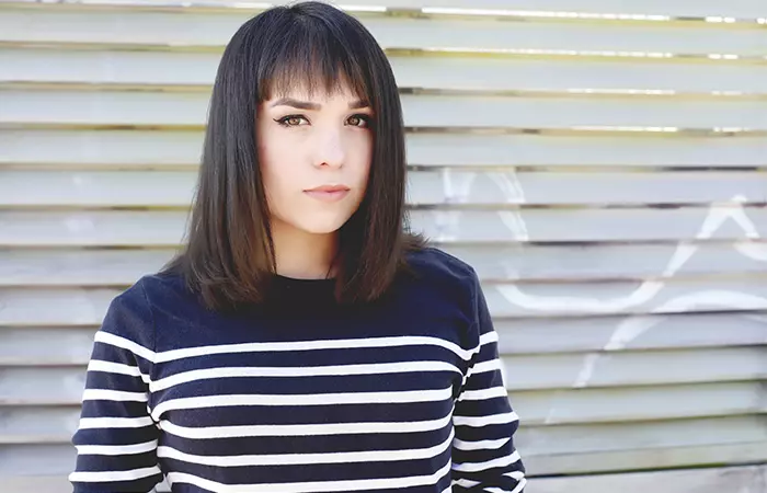 A woman with growing out bangs posing looking at the camera